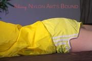 Lucy tied and gagged on bedposts face-down position wearing a sexy yellow shiny nylon shorts and a yellow rain jacket (Pics)