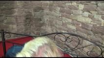 Pia tied and gagged on a princess bed in an old cellar wearing a sexy dark blue nylon shorts and an oldschool red rain jacket (Video)
