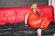 Pia tied and gagged with nack ties on a bed wearing a sexy red shiny nylon rainwear catsuit (Pics)
