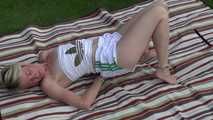 Sexy Sonja wearing a white shiny nylon shorts and a white top being tied with cuffs lying on the garden (Video)