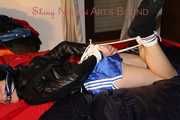 SEXY LUCY wearing a blue shiny nylon shorts and a black shiny rain jacket being tied and gagged with ropes and a clothgag on the bed (Pics)