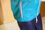 Mara wearing a blue rain pants and a green rain jacket posing infront of a mirror (Pics)