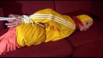 Lucy tied, gagged and hooded on a red sofa wearing a sexy orange shiny nylon pants and a yellow rain jacket (Video)