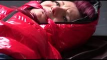 Mara tied and gagged on bed wearing a sexy shiny red down jacket and a blue rain pants (Video)