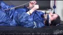Lucy ties and gagges herself with cuffs on a bed wearing sexy blue shiny nylon rainwear (Video)