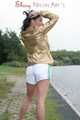 Watching out beautiful archive girl wearing a white shiny nylon shorts and a golden rain jacket posing outdoor (Pics)