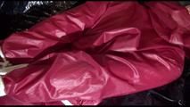 Mara tied and gagged on a bed wearing a supersexy black leggins with a red rain jacket and a red shiny nylon shorts over it (Video)