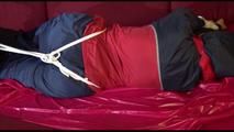 Lucy tied and gagged with ropes and a cloth gag on a sofa wearing a blue/red rainwear combination (Video)