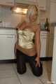 Natural busty Martina posing in a golden corsage, black leggins, pantyhose and heels in the kitchen