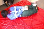 Jill tied and gagged on bed wearing a shiny black pants and a shiny blue rain jacket (Pics)