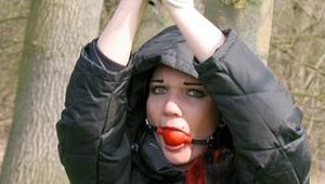 Jill tied, gagged and hooded on a tree outdoor wearing a shiny black down jacket (Pics)