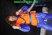 Stella helps Ronja to pullover a lifevest the other way round both wearing shiny nylon downwear (Pics)