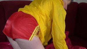 Lucy preparing her sofa with a shiny nylon cloth wearing a sexy red/yellow shiny nylon shorts and a yellow rain jackcet (Video)