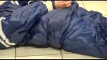 Jill tied and gagged on the floor in an old cellar wearing a shiny blue PVC sauna suit (Video)