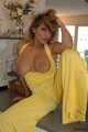 Busty Alexandra posing in a yellow jumbsuit in the kitchen