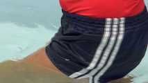 Watching Sandra wearing a sexy darkblue shiny nylon shorts and a red tshirt lying in the sun and taking a bath in the swimming pool (Video)