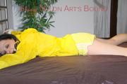 Lucy tied and gagged on bedposts face-down position wearing a sexy yellow shiny nylon shorts and a yellow rain jacket (Pics)