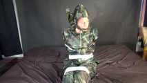 Watching sexy Pia being tied and gagged with tape on a bed wearing a sexy camouflage shiny nylon rainpants and a rainjacket as well as yellow rubber boots (Video)