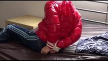 Mara tied and gagged on bed wearing a sexy shiny red down jacket and a blue rain pants (Video)