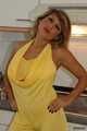 Busty Alexandra posing in a yellow jumbsuit in the kitchen