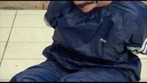 Jill tied and gagged on the floor in an old cellar wearing a shiny blue PVC sauna suit (Video)