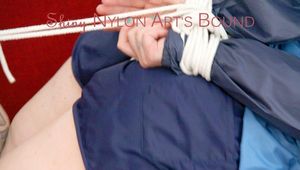 Jill tied, gagged and hooded with ropes on as sofa wearing a blue shiny nylon shorts and a blue oldschool rain jacket (Pics) 