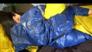 Lucy playing with zipper and lolling on a bed wearing supersexy blue AGU rainwear (Video)