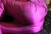 Watching sexy Mara lying on a black shiny sofa wearing a sexy pink downsuit reading a book (Pics)