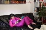 Watching sexy Mara lying on a black shiny sofa wearing a sexy pink downsuit reading a book (Pics)