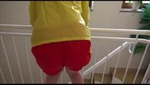 Pia tied and gagged on a stairway with cuffs wearing a sexy red/yellow shiny nylon shorts and a yellow rain jacket (Video)