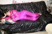 Watching sexy Mara lying on a black shiny sofa wearing a sexy pink downsuit reading a book (Pics)