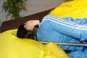 Lucy tied and gagged in a shiny nylon bed with on a bar behind her back and with a cloth gag wearing a blue shiny nylon shorts and a lightblue rain jacket (Pics)