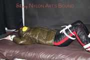 Watching Jill being tied on a bed wearing a shiny nylon rain jacket and a down jacket as well as a rain pants being double hooded and gagged with a ballgag (Pics)