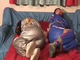 Jill and another girl tied and gagged with tape on a bed wearing beatiful shiny PVC suits (Video)