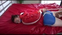 Jill wearing a blue shiny nylon shorts and a red shiny nylon jacket tied and gagged on bed (Video)